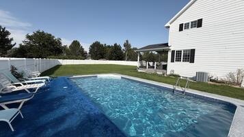 A swimming pool with a blue carpeted deck and white lounge chairs.