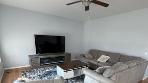 A living room with a grey sofa, a coffee table, a TV, and a ceiling fan.