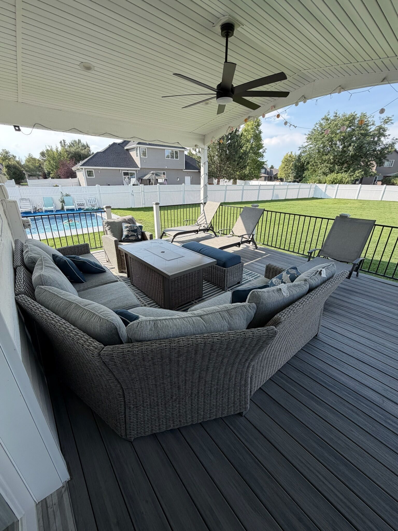 Een overdekt terras met een modulaire bank, een tafel en stoelen.
