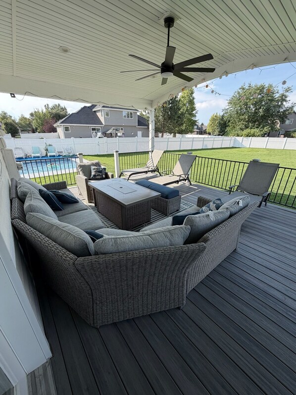 A covered outdoor deck with a sectional sofa, a table, and chairs.