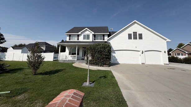 A two-story residential house with a front porch, a garage, and a well-maintained lawn.