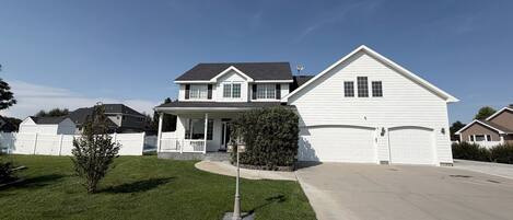 A two-story residential house with a front porch, a garage, and a well-maintained lawn.