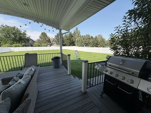 Un patio techado con una parrilla, asientos al aire libre y césped.