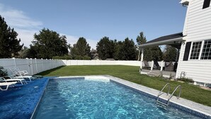 A rectangular swimming pool with a clear blue water surface, surrounded by a pebble-textured deck.
