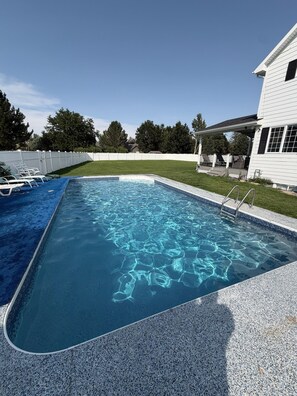 A rectangular swimming pool with a clear blue water surface, surrounded by a pebble-textured deck. - Spacious Pool house in adorable Billings with AC. Big backyard + Covered Patio. (Billings)