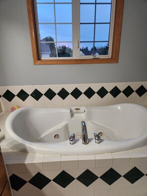 A bathroom with a white freestanding bathtub, a window above it, and a black and white patterned tile backsplash. - Spacious Pool house in adorable Billings with AC. Big backyard + Covered Patio. (Billings)