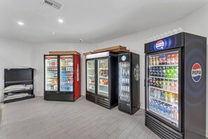 En række automater med Pepsi-branding, et sort køleskab og en reol med sammenfoldede ting.
