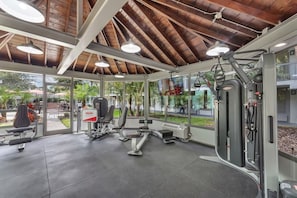 Ein Fitnessstudio mit unterschiedlichen Trainingsgeräten, großen Fenstern und Blick nach außen.