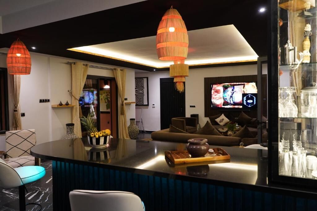 Un salon moderne doté d’un grand téléviseur à écran plat, d’un canapé et d’un coin repas avec une table à plateau en verre.