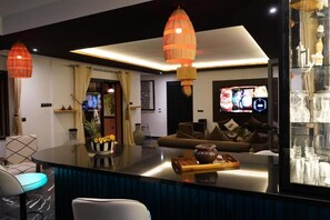 Una sala de estar moderna con un televisor de pantalla plana grande, un sofá y una zona de comedor con una mesa de vidrio.
