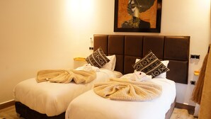 A hotel room with two beds, a large framed artwork above the beds, and a bedside table with a lamp. - Art Gallery Design Apartment Marrakech (Marrakech)