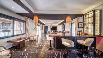 Een moderne hotelentree met een marmeren vloer, een bar en zithoekjes.