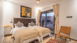 A bedroom with a large bed, a chair, a painting, and a view of the outside. - Art Gallery Design Apartment Marrakech (Marrakech)
