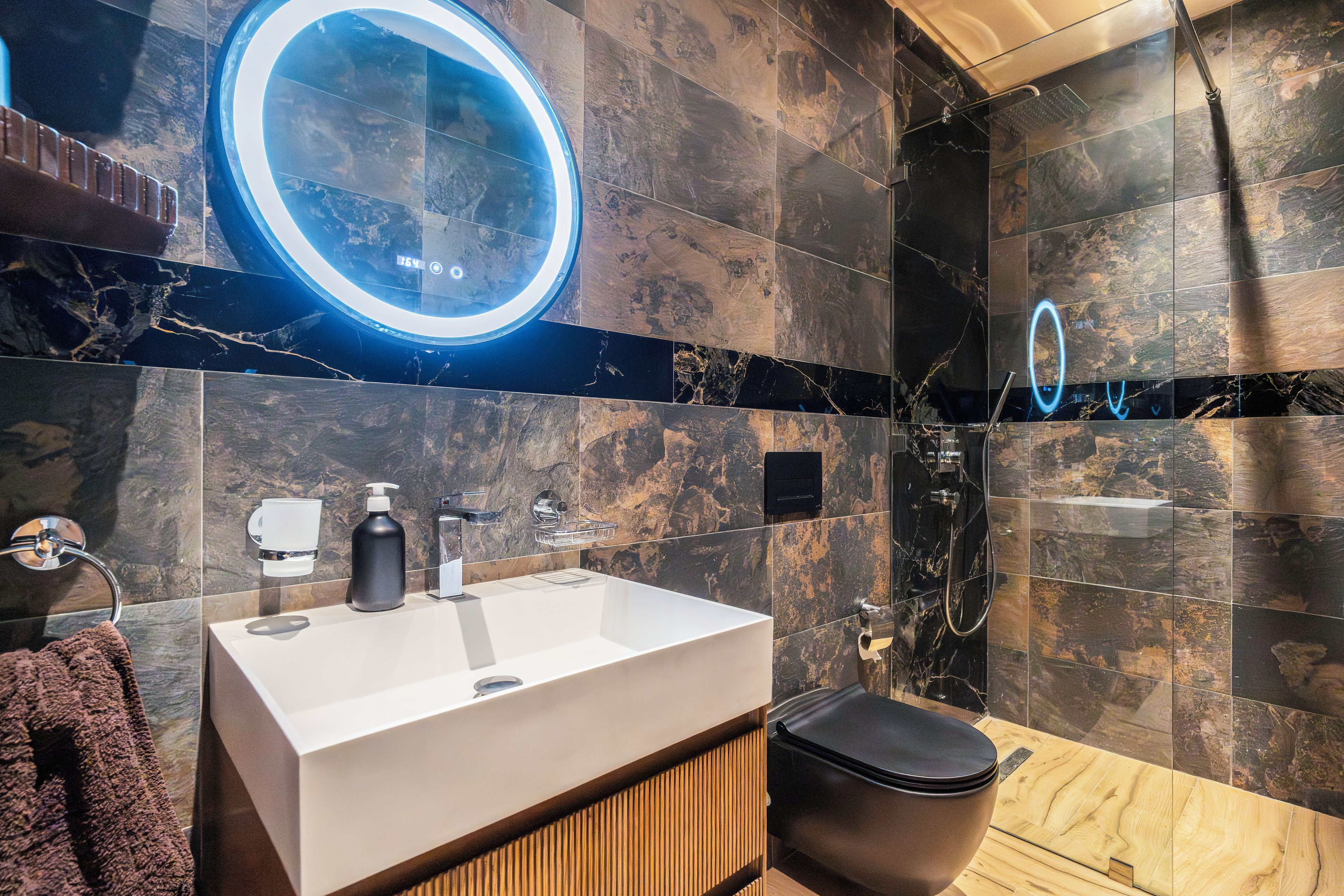 A modern bathroom with a large mirror, a sink, and a shower area.
