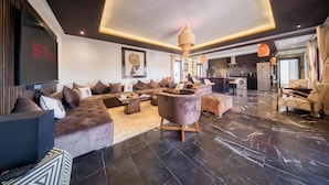 A modern living room with a sectional sofa, a coffee table, and a large TV screen. - Art Gallery Design Apartment Marrakech (Marrakech)