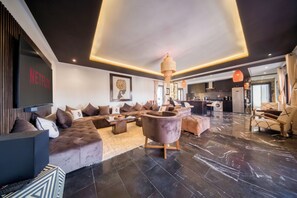 Una sala de estar moderna con un sofá modular, una mesa de centro y una pantalla de televisión grande.