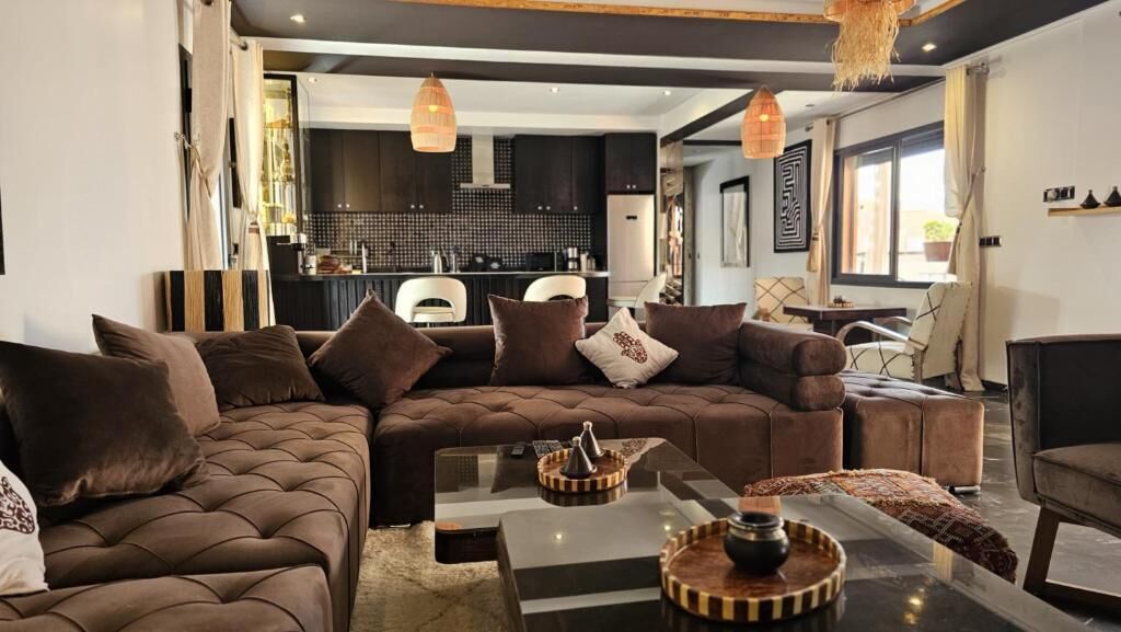 Un salon moderne avec un canapé d’angle, une table basse et un coin repas à l’arrière-plan.