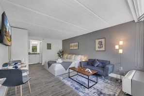 Ein modernes Wohnzimmer mit einer Couch, einem Couchtisch und einem Essbereich mit Stühlen und einem Tisch für zwei Personen.