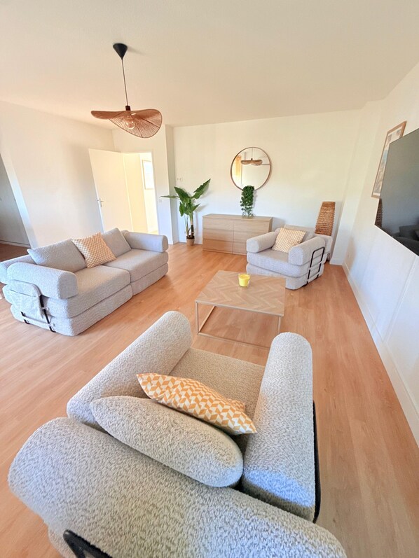 A modern living room with two sofas, a coffee table, and a hanging light fixture.