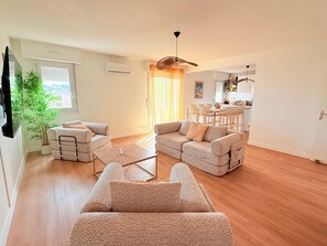 A living room with a sofa, a coffee table, and a dining area with chairs.