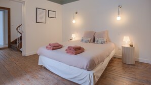 Un dormitori amb un llit, dues làmpades de nit, una tauleta de nit i una escala.