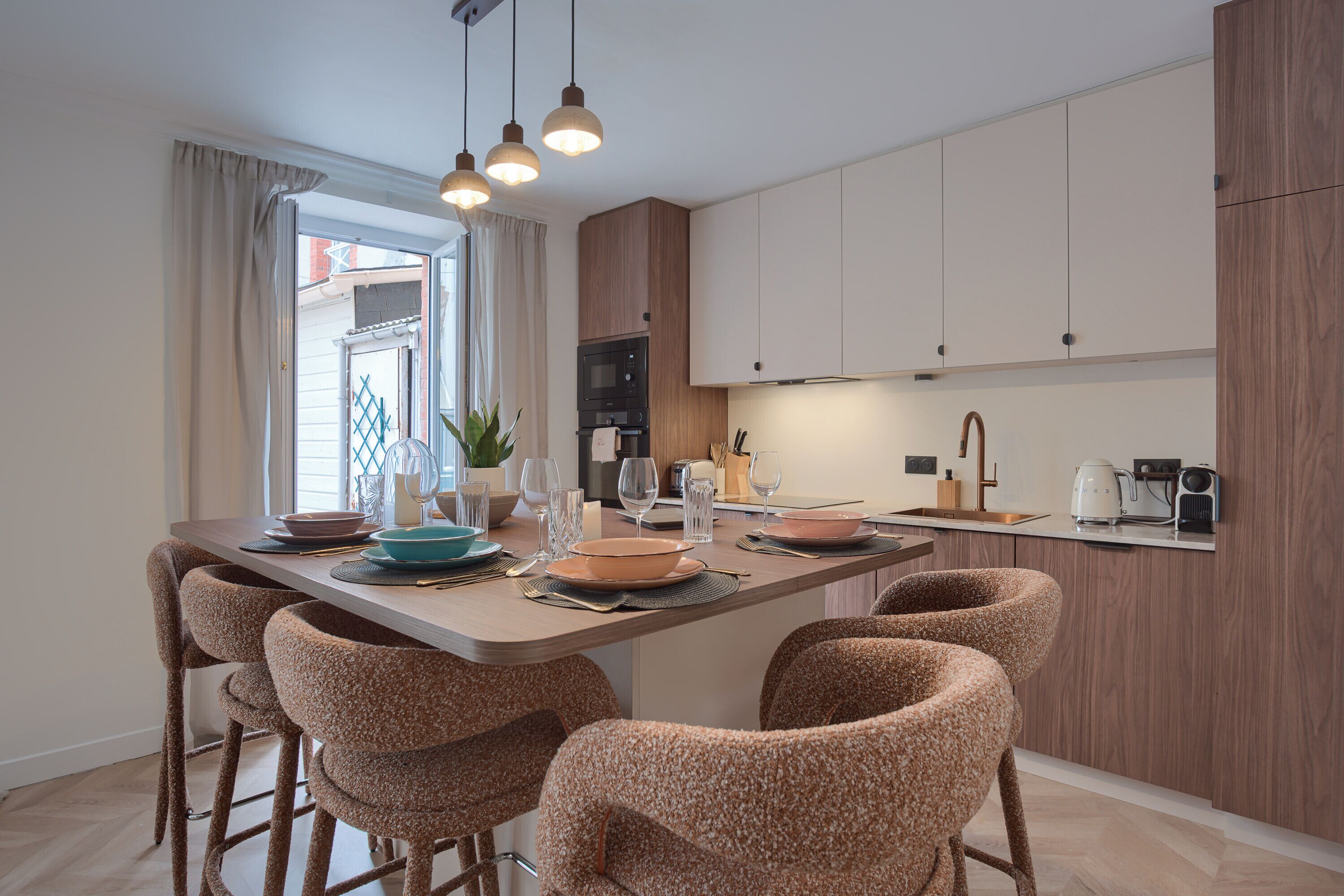 A modern kitchen with a central island, bar stools, and a dining table set for four.