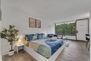 Ein modernes Schlafzimmer mit einem großen Bett, einem Schreibtisch und Blick ins Freie.
