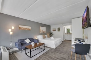 Une chambre d’hôtel moderne équipée d’un canapé, d’un lit, d’un coin repas et d’une télévision.