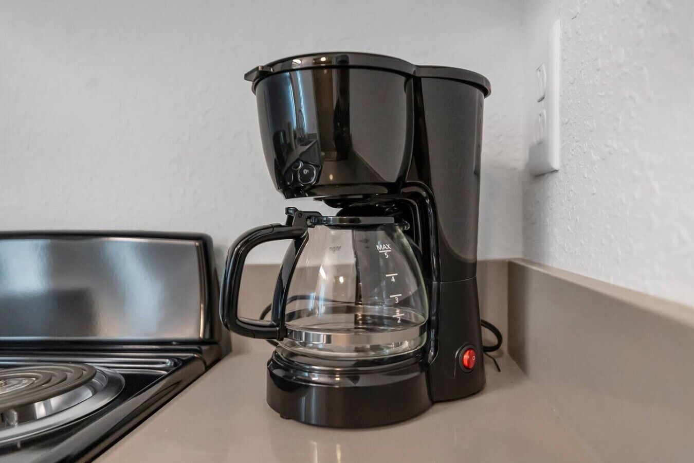 Eine schwarze Kaffeemaschine mit Glasbehälter auf einer Küchenarbeitsplatte.