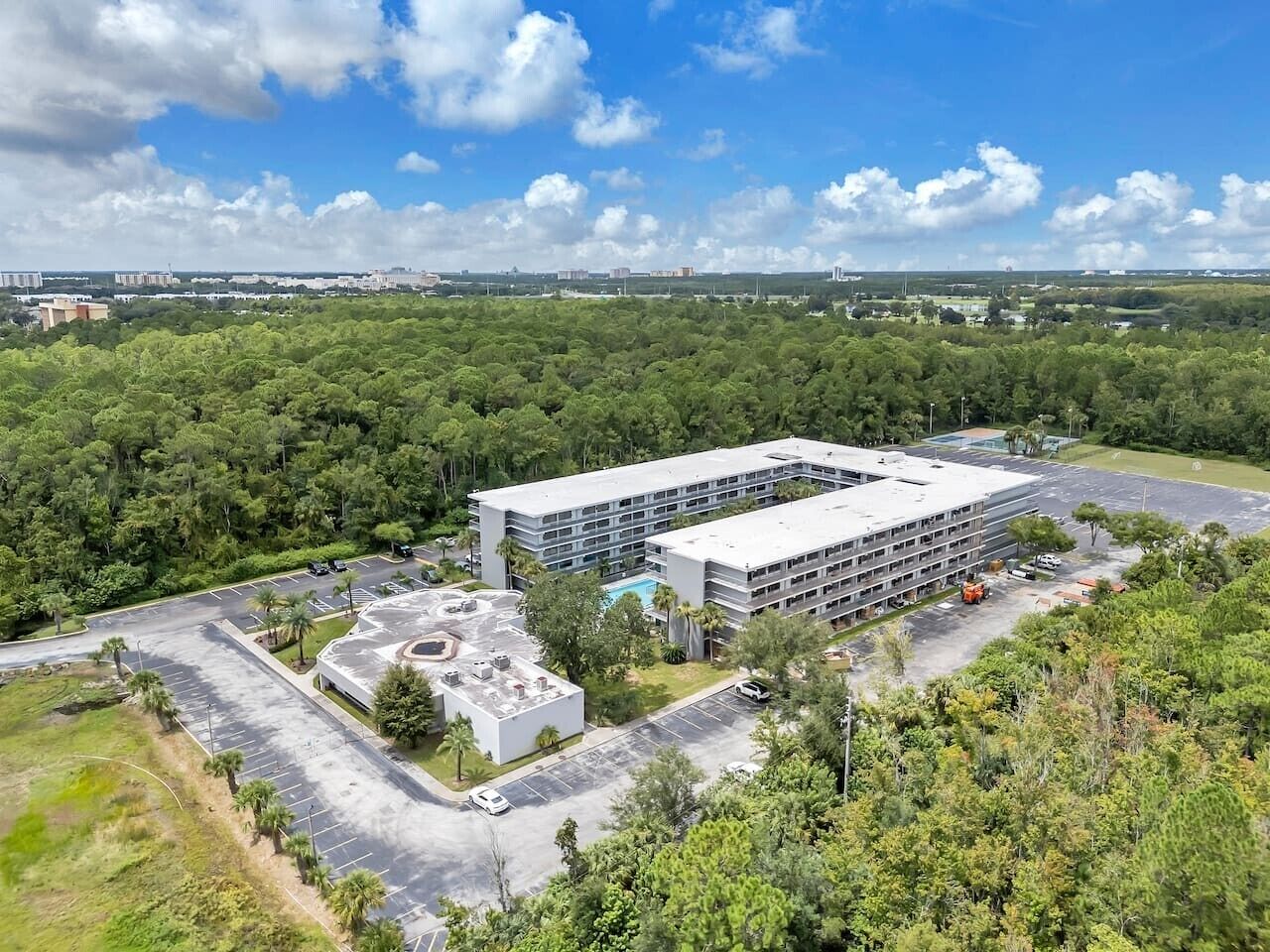 Een meerhoog hotel met een parkeerplaats en een zwembad.
