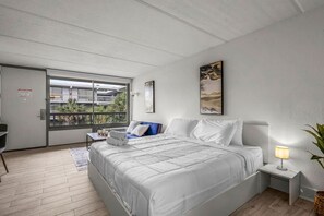 A bedroom with a bed, a desk, a chair, a window with a view, and a nightstand with a lamp. - Top Disney Location w Pool & Free Parking | Orl (Kissimmee)