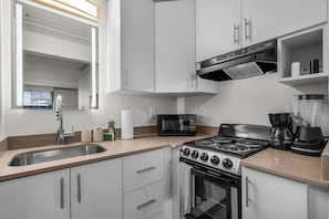 Een moderne keuken met een kookplaat, magnetron en koffiezetapparaat.