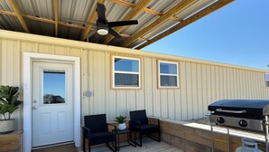A covered outdoor deck with a grill, two chairs, and a ceiling fan. - 3-bedroom house in peaceful Pottsville (Pottsville)