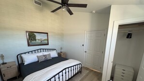 A bedroom with a bed, a ceiling fan, a nightstand, a bedside table, a door, and a chair. - 3-bedroom house in peaceful Pottsville (Pottsville)
