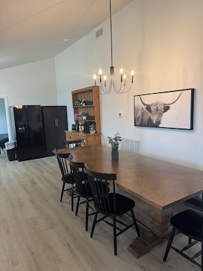 A modern kitchen with black appliances, a wooden dining table, and a chandelier. - 3-bedroom house in peaceful Pottsville (Pottsville)