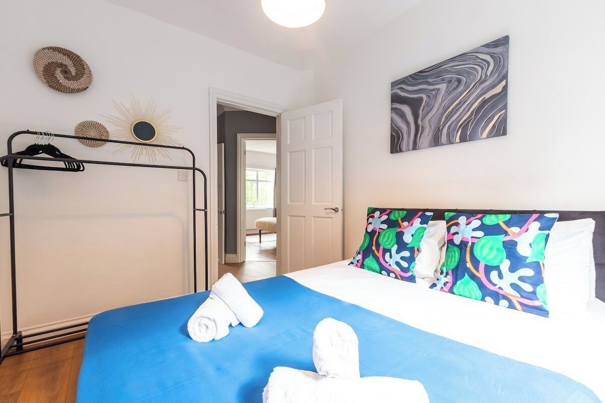A hotel room with a bed, a wardrobe, and a door leading to another room.