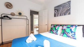 A hotel room with a bed, a wardrobe, and a door leading to another room.