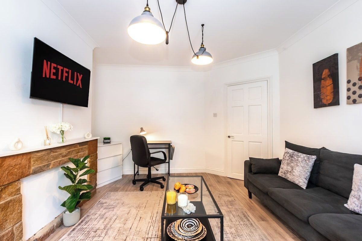 Een moderne woonkamer met een open haard, een bank, een salontafel en een aan de muur bevestigde televisie.