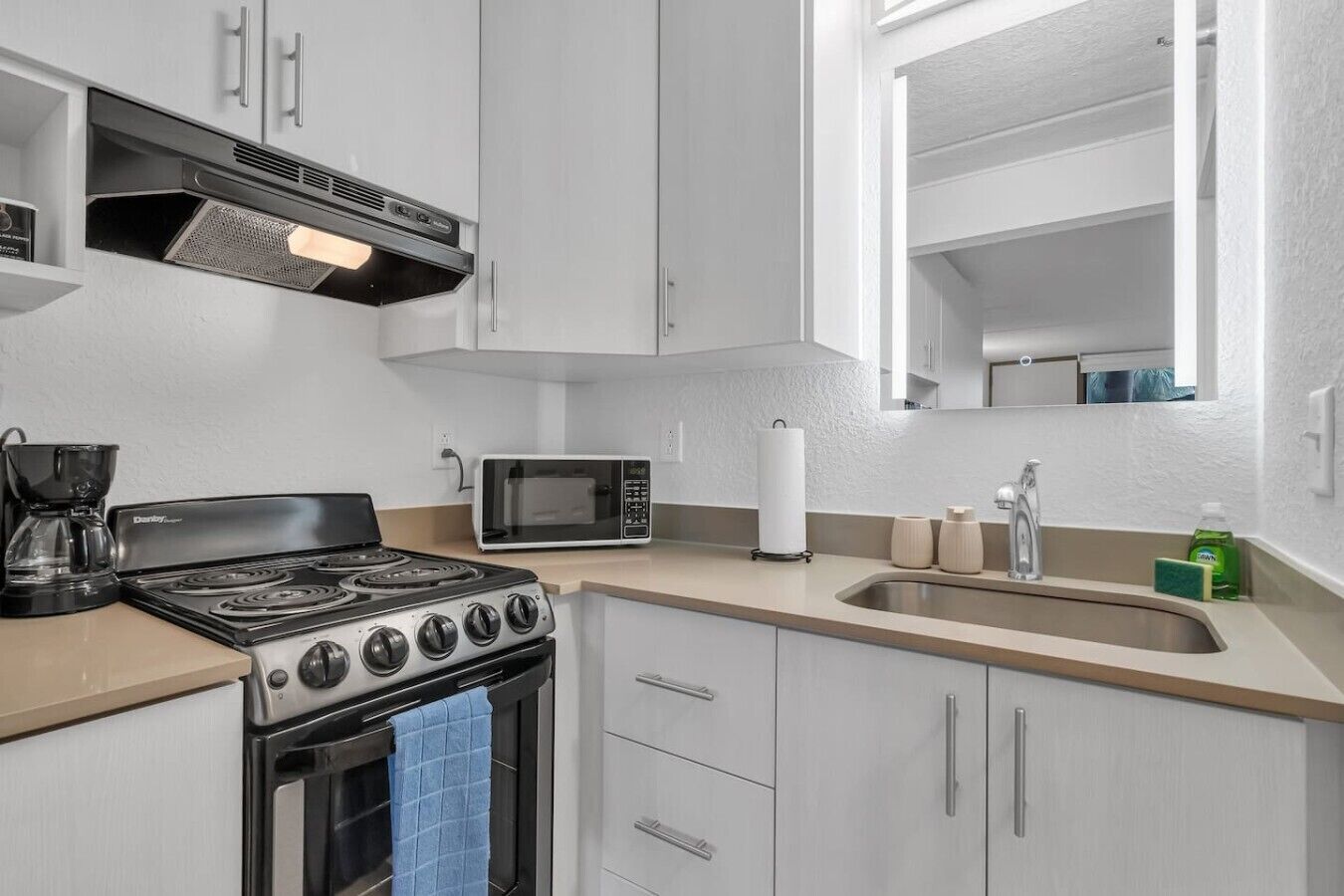 A modern kitchen with a gas stove, microwave, and stainless steel sink.