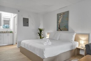 A hotel room with a bed, bedside table, lamp, and a painting of a bird on the wall. - Resort Condo 7 Min to Disney | Free Parking | Orl (Kissimmee)