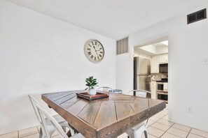 Un coin repas avec une table en bois, des chaises, une horloge et une plante en pot.