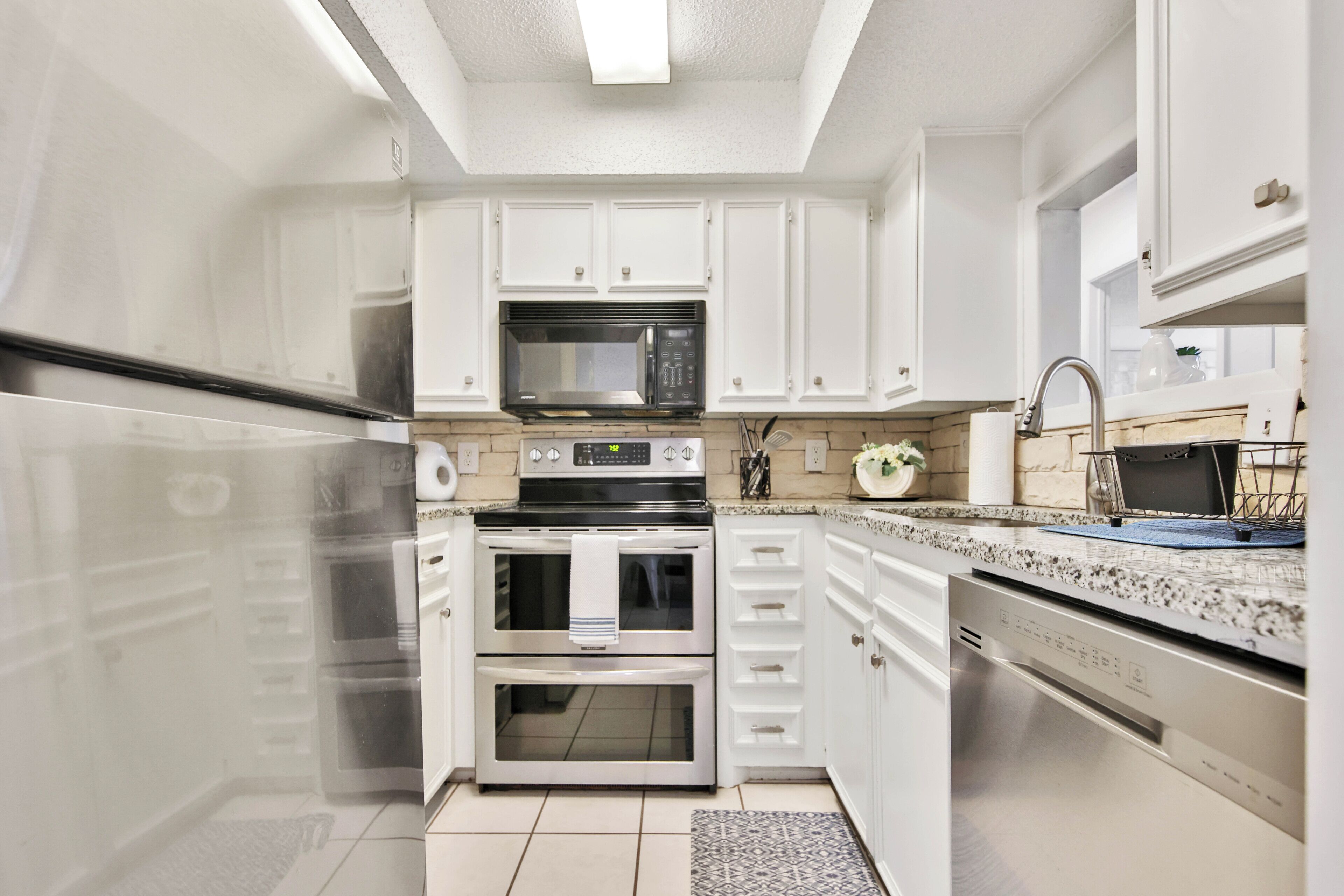 A modern kitchen with white cabinetry, stainless steel appliances, and a granite countertop.