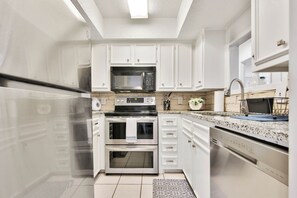 Una cocina moderna con armarios blancos, electrodomésticos de acero inoxidable y encimera de granito.