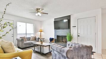 A living room with a fireplace, a ceiling fan, and a sofa.