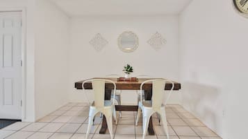 A dining area with a wooden table, white chairs, and decorative wall mirrors.