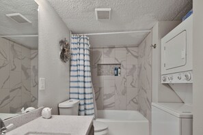 Une salle de bain équipée de toilettes, d’un lavabo, d’une douche et d’un lave-linge.