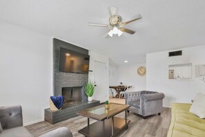 Una sala de estar con chimenea, un sofá, una mesa de centro y un ventilador de techo.