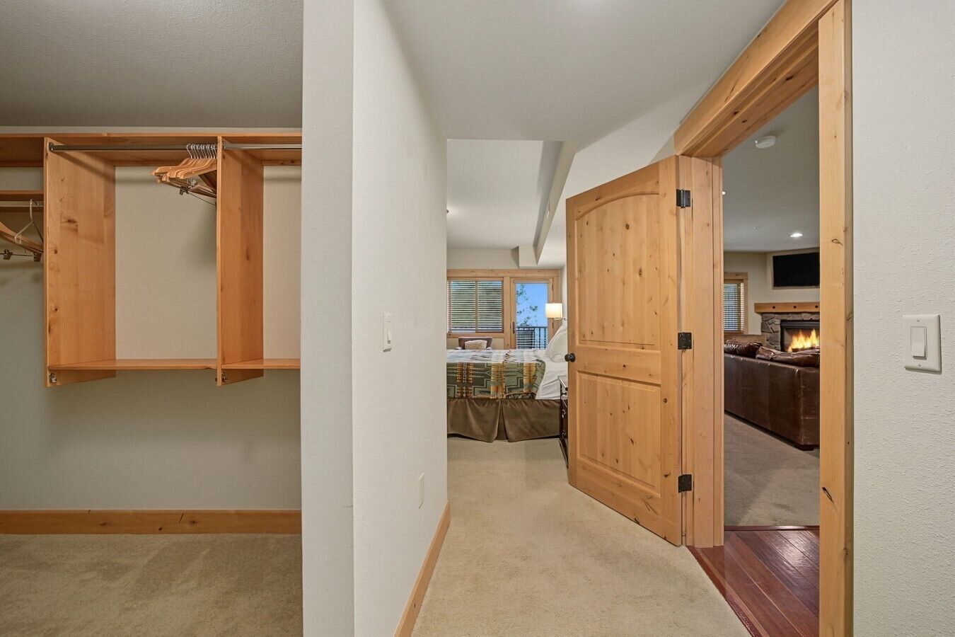A hallway leading to a bedroom with a closet and a living area with a fireplace.