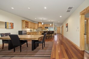 Een moderne keuken met houten kastjes, een zithoek met een houten tafel en stoelen, en een gang met houten vloeren.