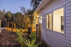 A residential property with a wooden deck, a well-maintained garden, and a house with large windows.